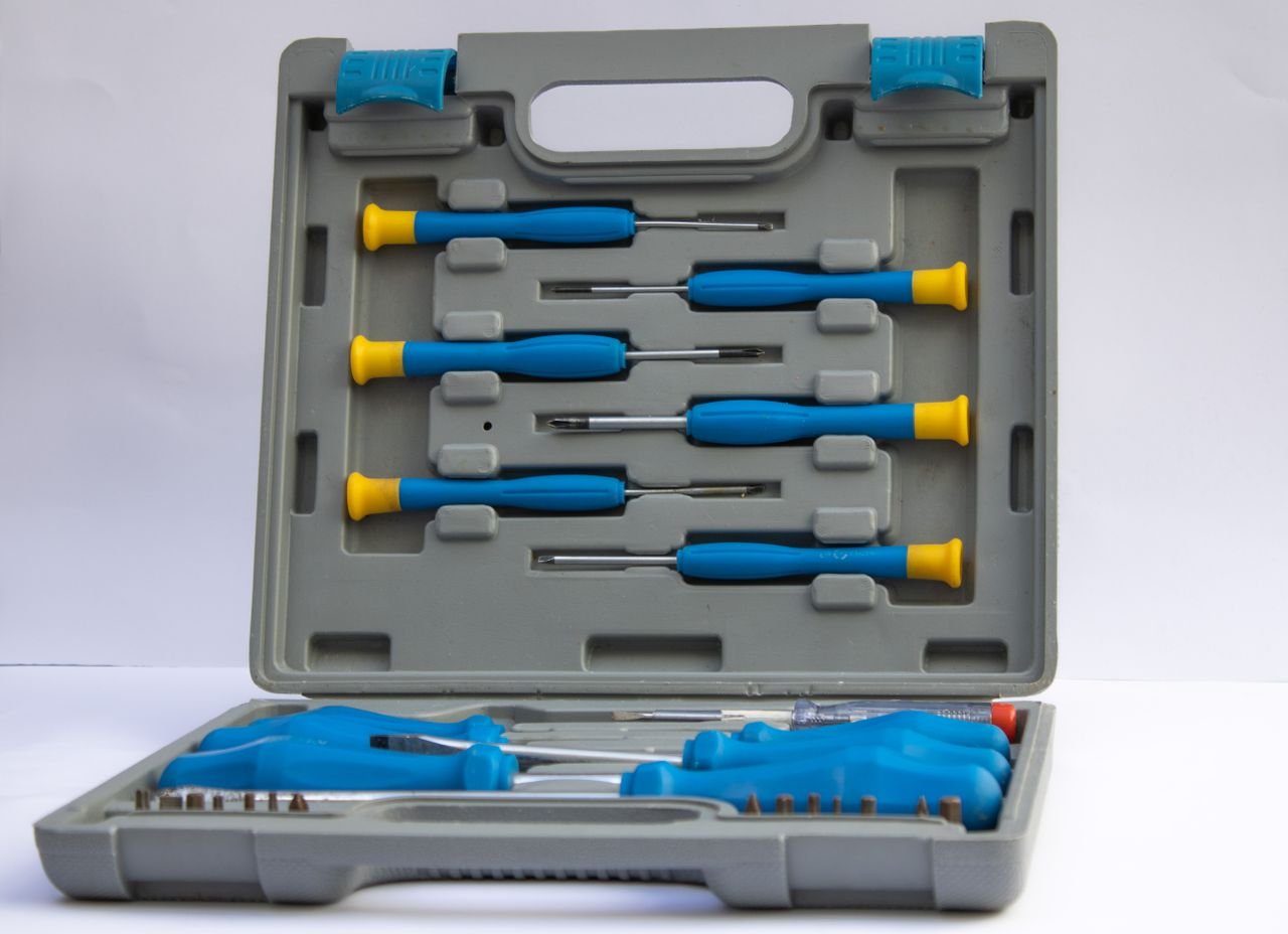 An open gray plastic toolbox displaying an assorted set of screwdrivers with blue handles.